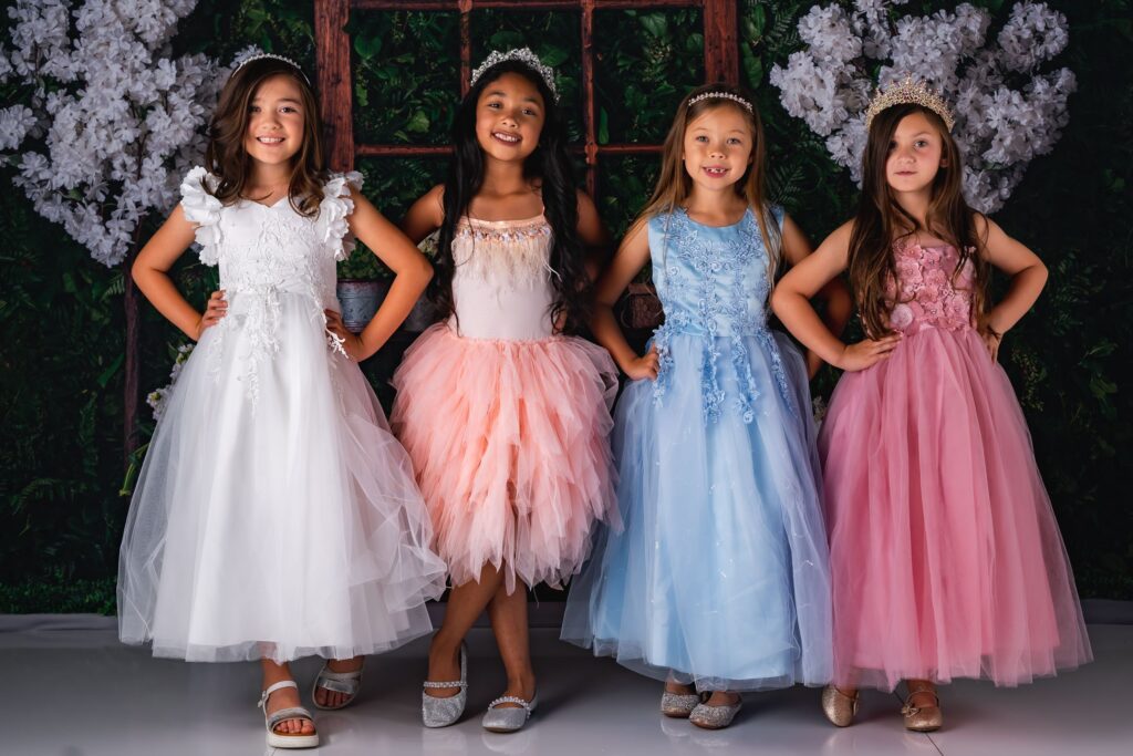 pexels-photo-17722721-17722721 A cheerful group of girls in colorful dresses and crowns posing happily indoors.